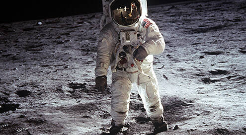 Foto eines Astronauten im weißen Raumanzug auf Mondoberfläche. Hintergrund schwarz.