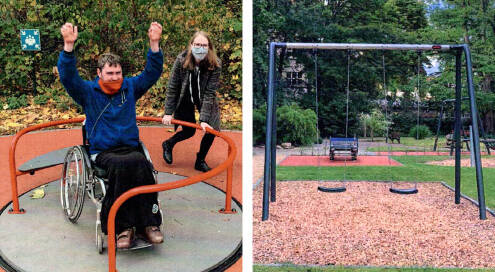 Rollstuhl-Karussell auf einem inklusiven Spielplatz, Junge im Rollstuhl sitzt im Karussell, er freut sich und hat die Arme in der Luft, Frau gibt Anschwung. Zwei Schaukeln auf einem inklusiven Spielplatz, im Hintergrund Bäume und andere Spielgeräte, drumherum Rasen.
